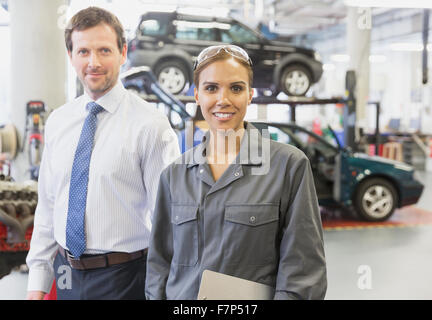 Porträt zuversichtlich Geschäftsmann und weibliche Mechaniker im Auto Werkstatt Stockfoto