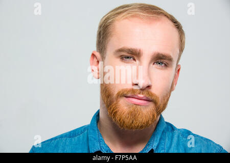 Porträt von Ernst nachdenklich bärtigen hübschen jungen Mann, die Kamera mit Blick auf weißem Hintergrund Stockfoto