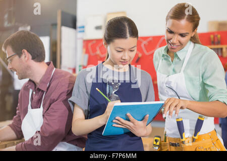 Weibliche Tischler Überprüfung Pläne in Werkstatt Stockfoto