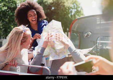 Verspielte Freunde mit Karte auf Doppeldecker-bus Stockfoto