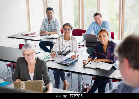 Lächelnd Schüler Lehrer in der Erwachsenenbildung Klassenzimmer anschauen Stockfoto