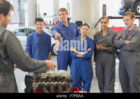 Mechaniker und Studenten diskutieren Automotor in Autowerkstatt Stockfoto