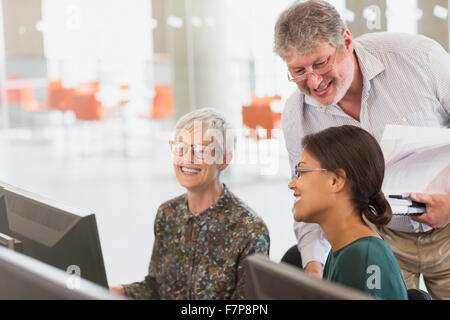 Lächelnde Studenten sprechen am Computer im Klassenzimmer der Erwachsenenbildung Stockfoto