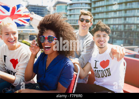 Porträt begeisterte Freunde mit britischer Flagge fahren Doppeldecker-bus Stockfoto