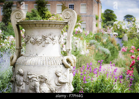 Grenzen in voller Blüte an Killerton, Devon, im Juli, mit einem klassischen Stil Urn im Vordergrund und das Haus im Hintergrund zu sehen. Stockfoto