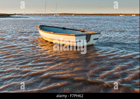 Eine Jolle schwimmt im kalten Wasser auf einen luftigen Winter Sonnenuntergang in einem See in Norfolk. Stockfoto