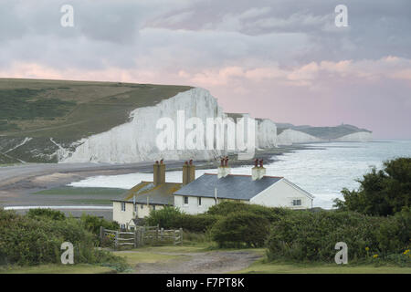 Stürmischer Himmel über Coastgard Hütten im Cuckmere Valley, East Sussex, mit den sieben Schwestern jenseits gesehen. Stockfoto