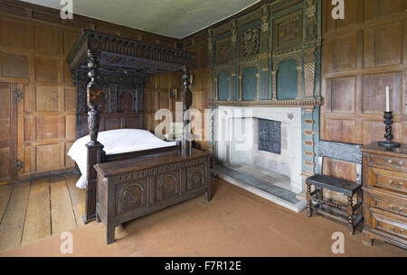 Henry Ferrers Schlafzimmer, Baddesley Clinton, Warwickshire. Die Schnitzereien und Intarsien Himmelbett Eiche Bettgestell erfolgte vom siebzehnten Jahrhundert Fragmente, die im 19. Jahrhundert zusammengestellt wurden. Der Kaminsims enthält die Wappen der Ferrers G Stockfoto