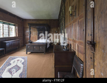 Henry Ferrers Schlafzimmer, Baddesley Clinton, Warwickshire. Die Schnitzereien und Intarsien Himmelbett Eiche Bettgestell erfolgte vom siebzehnten Jahrhundert Fragmente, die im 19. Jahrhundert zusammengestellt wurden. Der Kaminsims enthält die Wappen der Ferrers G Stockfoto