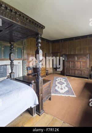 Henry Ferrers Schlafzimmer, Baddesley Clinton, Warwickshire. Die Schnitzereien und Intarsien Himmelbett Eiche Bettgestell erfolgte vom siebzehnten Jahrhundert Fragmente, die im 19. Jahrhundert zusammengestellt wurden. Der Kaminsims enthält die Wappen der Ferrers G Stockfoto