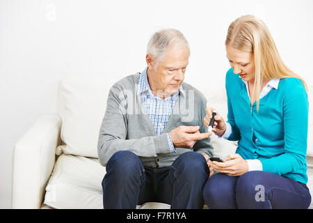 Junge Frau Bluttest für ältere Menschen mit Diabetes zu tun Stockfoto