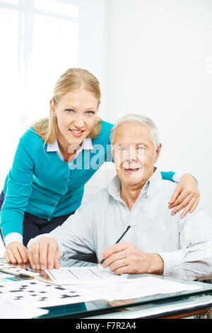 Familie mit älteren Mann lösen Kreuzworträtsel zu Hause für Gedächtnistraining Stockfoto