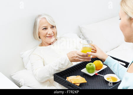 Alte Frau essen Frühstück im Bett mit ihrer Enkelin Stockfoto