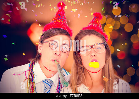 Zusammengesetztes Bild geeky Hipster einen Party-Hut mit Partei Horn bläst Stockfoto