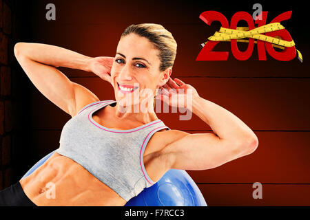 Zusammengesetztes Bild Fit Frau tun Sit Ups auf blau Gymnastikball lächelnd in die Kamera Stockfoto