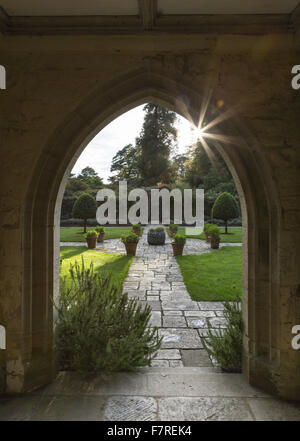 Blick auf den Vorplatz Garten bei Nymans, West Sussex, gesehen durch den Torbogen des Hauses Gartensaal Veranda, im Oktober. Stockfoto