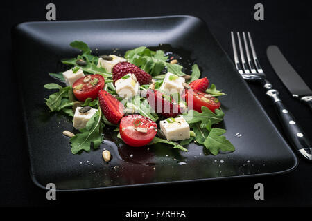 Erdbeer-Tomaten-Salat, Feta-Käse, Olivenöl und Besteck Stockfoto