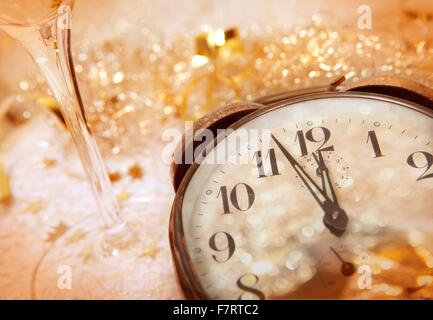 Eine Uhr zeigt in der Nähe von Mitternacht und ein Glas Sekt zum Jahreswechsel Stockfoto