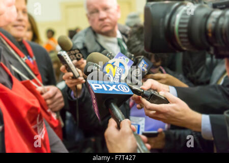 Mikrofone von Radio- und Fernsehstationen, gruppiert um Timothy Cardinal Dolan von Erzdiözese von New York, links, da er ein Interview an einem Thanksgiving Essen gibt verschenken auf Dienstag, 24. November 2015 in New York. (© Richard B. Levine) Stockfoto