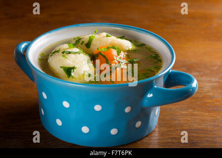 Hühnersuppe mit Knödel in blau Schüssel auf Holztisch Stockfoto