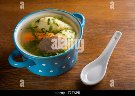 Hühnersuppe mit Knödel in blau Schüssel auf Holztisch Stockfoto