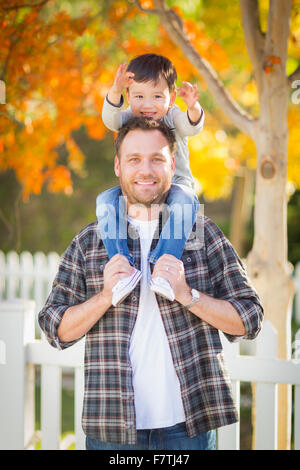 Happy Mixed Race junge Reiten Huckepack auf den Schultern der kaukasischen Vater. Stockfoto