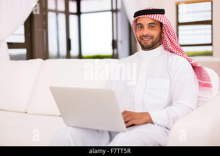 gut aussehende islamischen Mann mit Laptop im Wohnzimmer Stockfoto