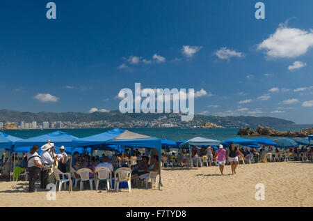 Mariachi Sänger und Musiker spielen für Touristen am Papagayo Strand in Acapulco, Mexiko Stockfoto