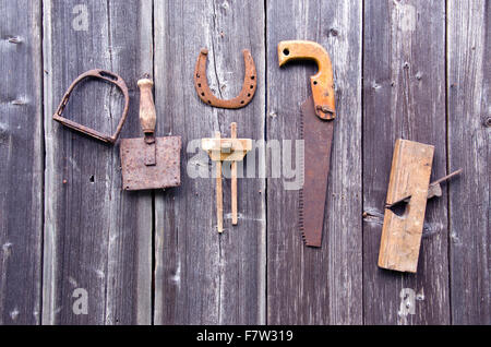 Alte rostige Werkzeuge grau Holz Bauernhof Scheune Wand hängen Stockfoto