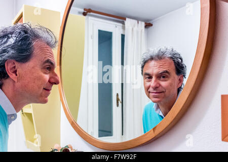 hübscher Mann mittleren Alters mit schönen Blick in den Spiegel schauen Stockfoto