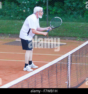 Senior woman Tennis spielen auf einem Kies-Gericht Stockfoto