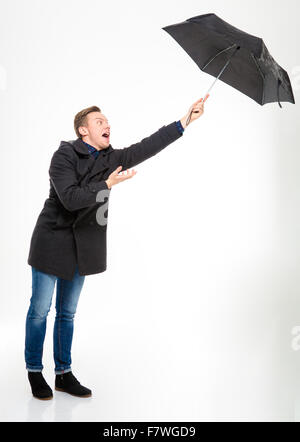 Ängstlich betonte jungen Mann im schwarzen Mantel und Jeans mit Dach wegfliegen auf weißem Hintergrund Stockfoto