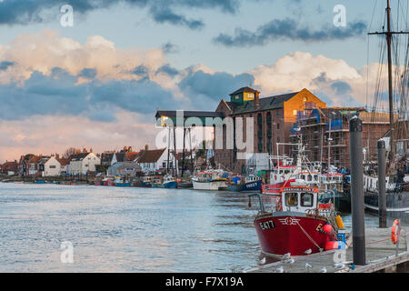 Boote bei Sonnenuntergang am Hafen in Wells nächsten The Sea Norfolk mit einem stürmischen Himmel im Hintergrund. Stockfoto