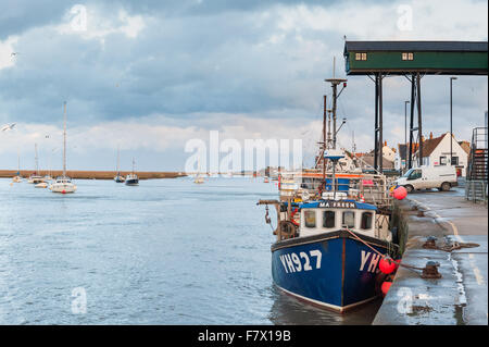 Boote bei Sonnenuntergang am Hafen in Wells nächsten The Sea Norfolk mit einem stürmischen Himmel im Hintergrund. Stockfoto