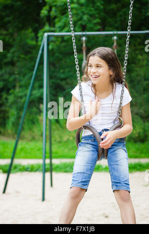 Mädchen sitzen auf einer Schaukel auf einem Spielplatz Stockfoto