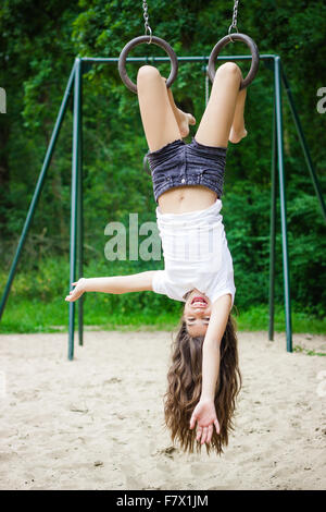 Mädchen auf einem Spielplatz kopfüber hängend Stockfoto