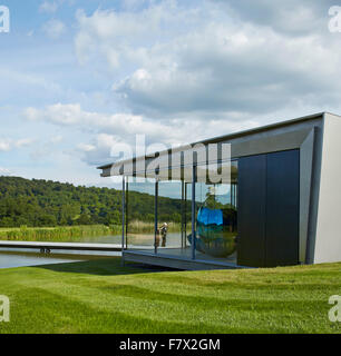 Höhe des See mit Steg, Glaspavillon und Jeff Koons-Skulptur. Insel-Pavillon und Steg, High Wycombe, vereint Stockfoto