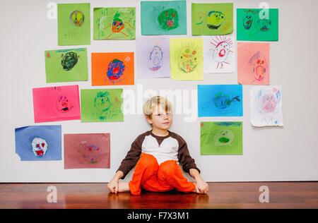 Junge sitzt durch die Wand in Gemälden und Zeichnungen Stockfoto