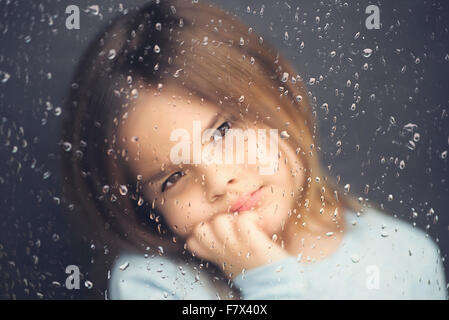 Blick aus einem Fenster an einem regnerischen Tag Mädchen Stockfoto