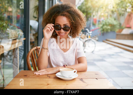 Porträt von hübschen jungen Mädchen im Café im Freien.  Junge Afrikanerin mit Sonnenbrille, Blick in die Kamera. Stockfoto