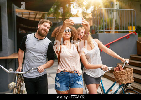 Junge afrikanische Frau nimmt ein Selbstporträt mit ihren Freunden. Afrikanische Frau nehmen Selfie mit Handy. Junge Freunde mit b Stockfoto