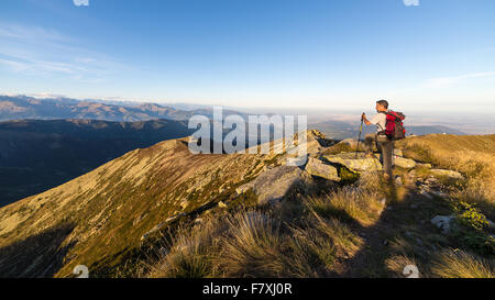 Mann, Wandern auf dem Bergrücken bei Sonnenuntergang und Blick auf majestätische Panorama der italienischen Alpen im Herbst. Weitwinkel-vie Stockfoto