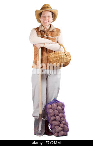 Glückliche pastorale Frau mit Spaten und geernteten Kartoffeln über weiß Stockfoto