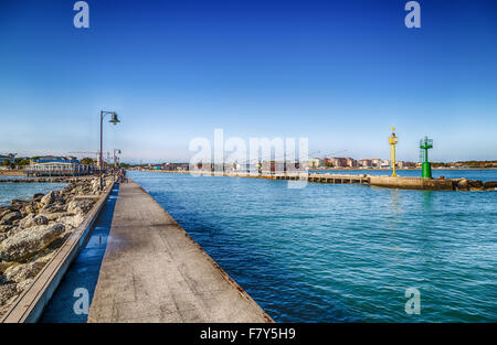 gelbe und grüne Leuchttürme auf dem Pier überfüllt mit Fischerhütten mit Blick auf die Paläste der Strand der Romagna Stockfoto