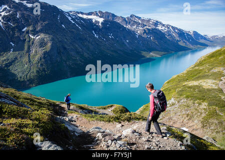 Zwei Wanderer über das türkisfarbene Wasser des See Gjende auf Memurubu, Gjendebu Wanderung im Nationalpark Jotunheimen Norwegen Stockfoto