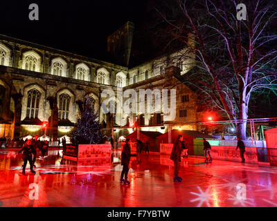 Skater auf der Eisbahn auf dem Gelände der Winchester Cathedral, Winchester, Hampshire, UK, wo die jährlichen Weihnachten markieren Stockfoto