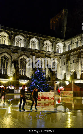 Skater auf der Eisbahn auf dem Gelände der Winchester Cathedral, Winchester, Hampshire, UK, wo die jährlichen Weihnachten markieren Stockfoto