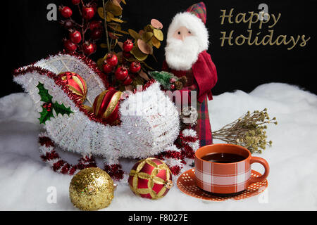 Wohnkultur Santa und seinem Schlitten auf Schnee Baum Dekorationen Tisch setzen und begleitet von einer warmen Tasse Kaffee Stockfoto