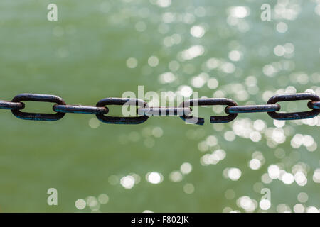 eine rostige Kette mit einem gebrochenen Ring Link über grünes Wasser Stockfoto