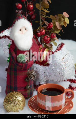 Wohnkultur Santa und seinem Schlitten auf Schnee Baum Dekorationen Tisch setzen und begleitet von einer warmen Tasse Kaffee Stockfoto